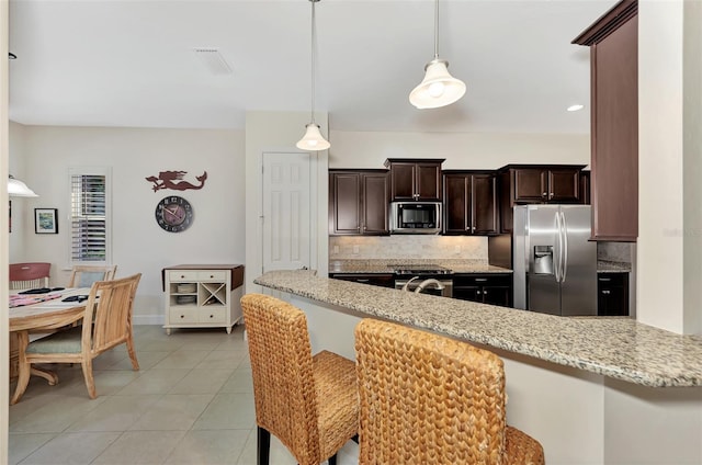 kitchen with pendant lighting, light stone countertops, appliances with stainless steel finishes, tasteful backsplash, and kitchen peninsula