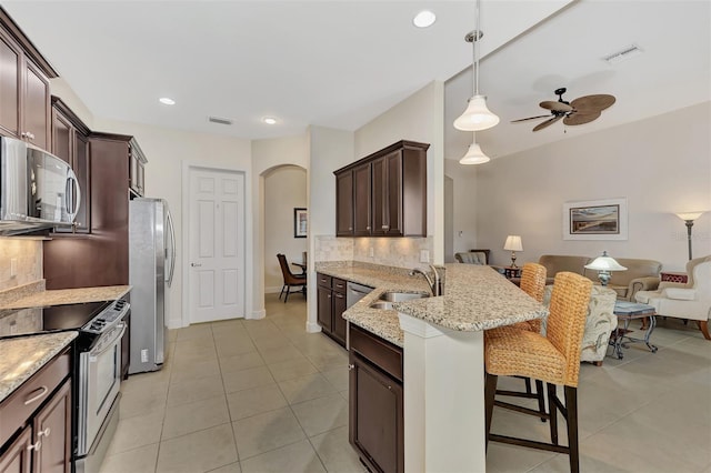 kitchen featuring sink, tasteful backsplash, decorative light fixtures, a breakfast bar, and appliances with stainless steel finishes