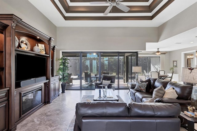 living room featuring a tray ceiling, crown molding, a towering ceiling, and ceiling fan