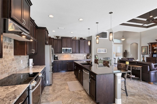 kitchen featuring pendant lighting, sink, appliances with stainless steel finishes, tasteful backsplash, and a kitchen bar