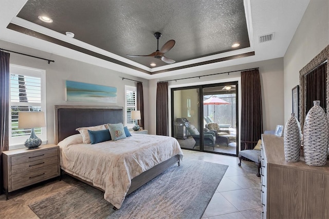 tiled bedroom with access to exterior, ceiling fan, and a raised ceiling