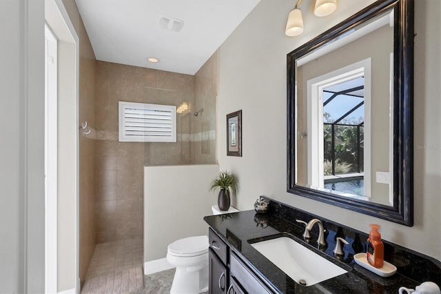 bathroom featuring toilet, vanity, and tiled shower