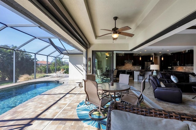 view of pool with a lanai, a patio area, ceiling fan, and an outdoor living space