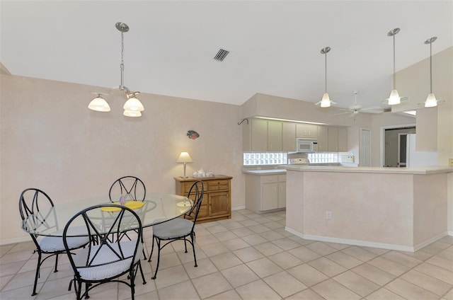 kitchen featuring ceiling fan, hanging light fixtures, kitchen peninsula, lofted ceiling, and light tile patterned floors