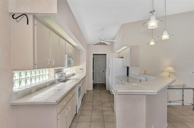 kitchen with kitchen peninsula, white appliances, tile countertops, and white cabinetry