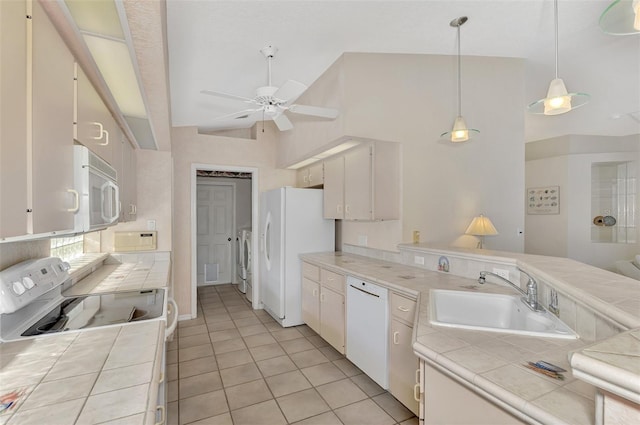 kitchen with tile countertops, white appliances, white cabinets, sink, and washer / dryer