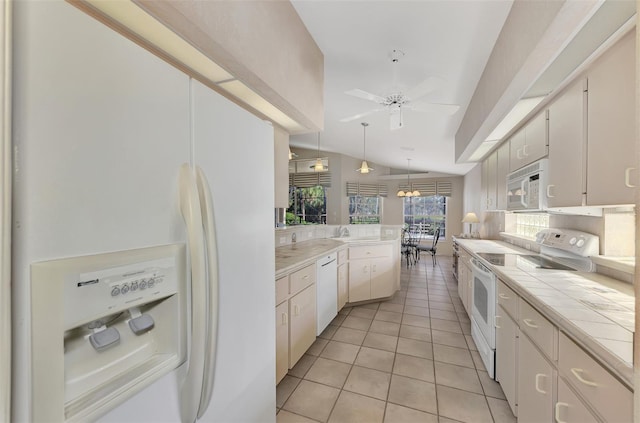 kitchen with tile countertops, white cabinetry, white appliances, and vaulted ceiling