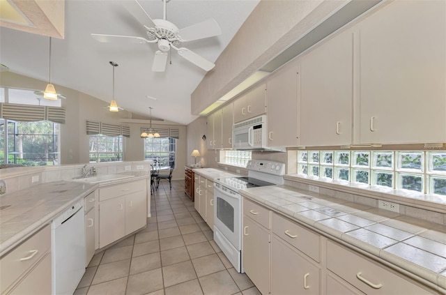 kitchen with tile counters, pendant lighting, vaulted ceiling, white appliances, and white cabinets