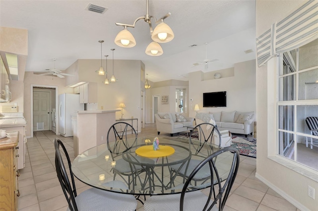 dining area featuring light tile patterned floors, ceiling fan with notable chandelier, and lofted ceiling