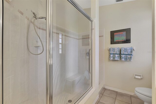 bathroom with tile patterned floors, a shower with door, and toilet