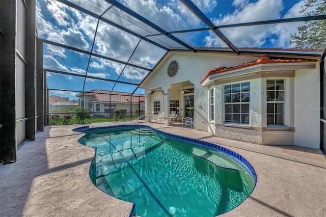 view of pool with glass enclosure, ceiling fan, and a patio area