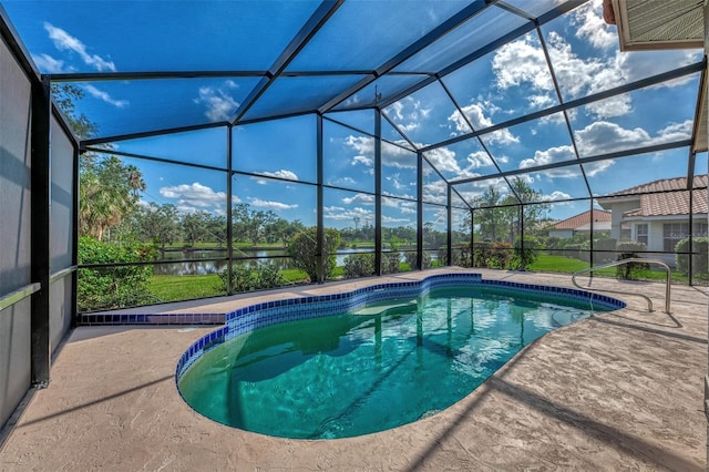 view of swimming pool with glass enclosure, a patio area, and a water view