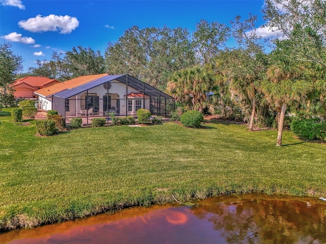 rear view of house featuring glass enclosure, a water view, and a yard