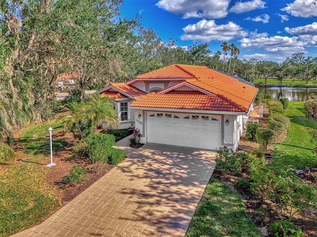 mediterranean / spanish-style home featuring a garage and a water view