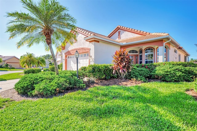 mediterranean / spanish-style home with a front yard and a garage