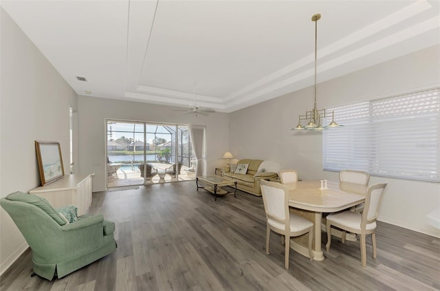 dining room featuring ceiling fan, wood-type flooring, and a raised ceiling