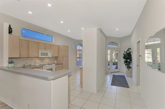 kitchen with kitchen peninsula, backsplash, white appliances, light brown cabinetry, and french doors