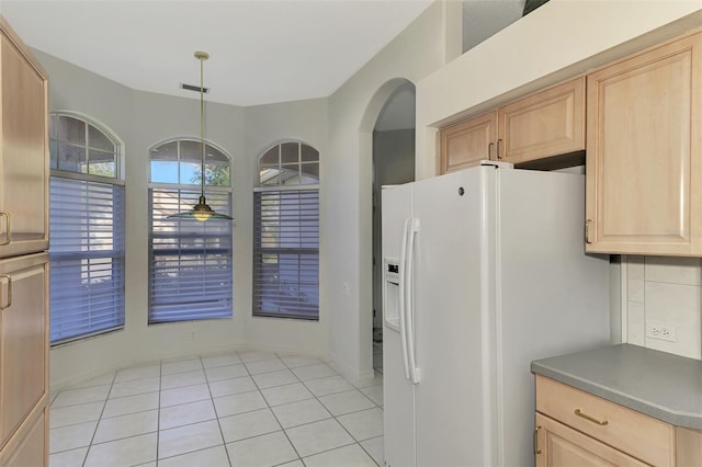 kitchen featuring decorative light fixtures, light tile patterned floors, light brown cabinets, and white refrigerator with ice dispenser