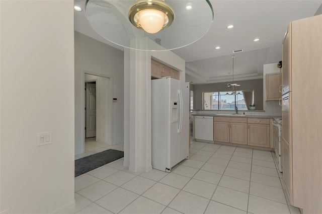 kitchen featuring white appliances, a tray ceiling, light brown cabinets, sink, and light tile patterned floors