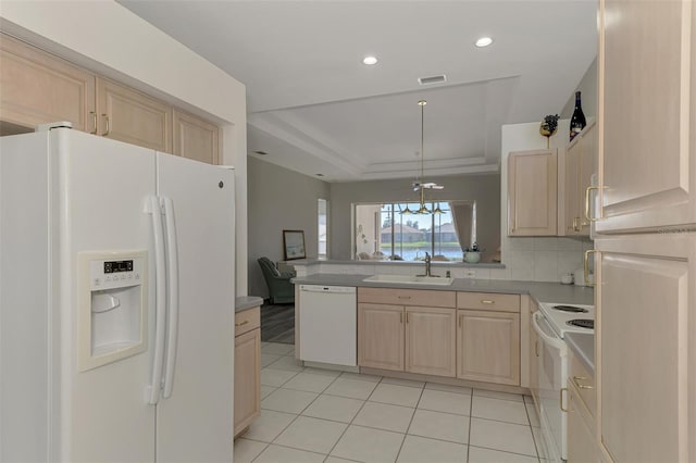 kitchen with light brown cabinetry, a tray ceiling, sink, and white appliances