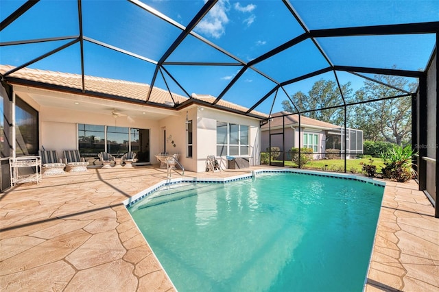 view of swimming pool with glass enclosure, a patio area, and ceiling fan