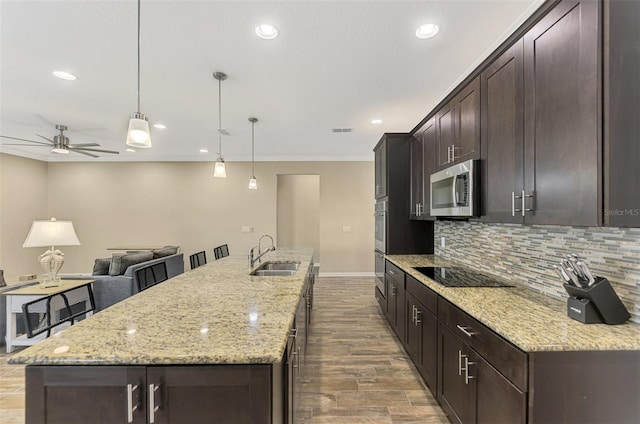 kitchen with sink, hanging light fixtures, light stone countertops, light hardwood / wood-style floors, and stainless steel appliances