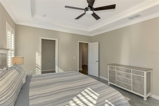 bedroom featuring a walk in closet, ornamental molding, ceiling fan, hardwood / wood-style floors, and a closet