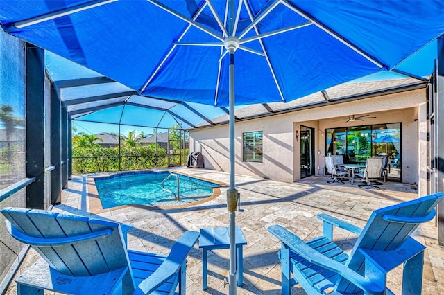 view of swimming pool with glass enclosure, ceiling fan, and a patio area