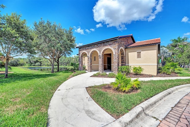 2148 La Palma Ave, Port Charlotte, FL 33953 - mediterranean / spanish-style home with a front lawn, stucco siding, a tile roof, stone siding, and a water view
