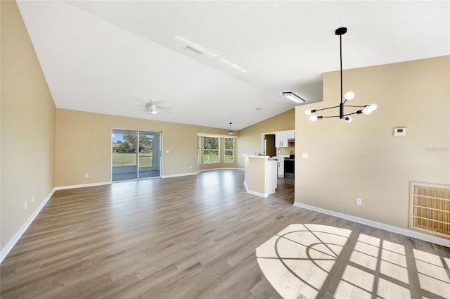 unfurnished living room with ceiling fan with notable chandelier, light wood-type flooring, and lofted ceiling