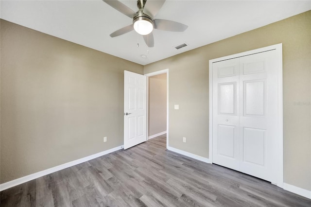 unfurnished bedroom with ceiling fan, light wood-type flooring, and a closet