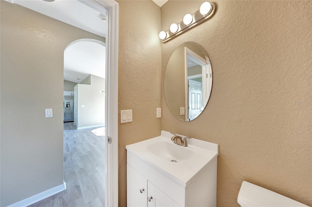 bathroom with hardwood / wood-style floors, vanity, and toilet