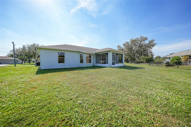 rear view of property featuring a sunroom and a yard