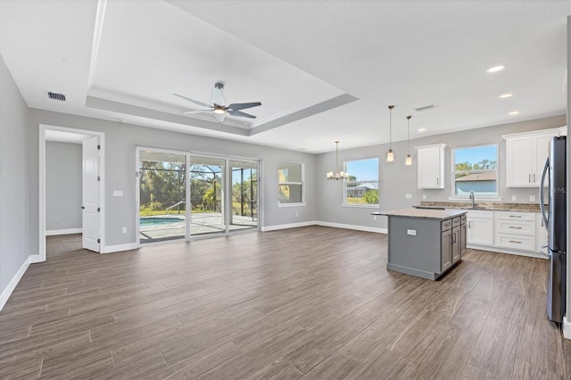 kitchen featuring hardwood / wood-style flooring, a center island, white cabinetry, hanging light fixtures, and stainless steel refrigerator