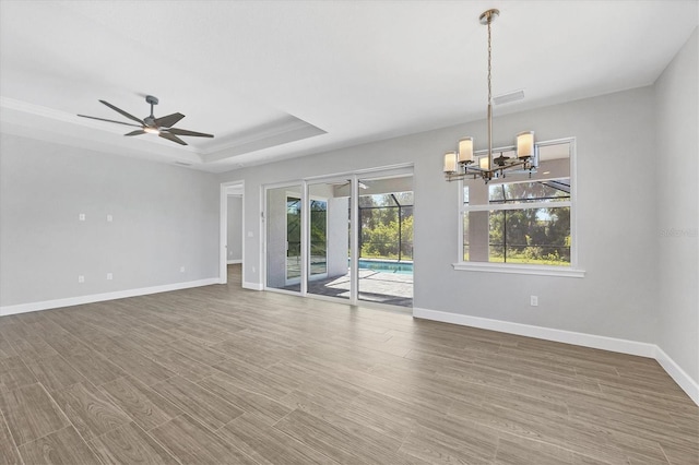 unfurnished room with hardwood / wood-style flooring, ceiling fan with notable chandelier, and a tray ceiling