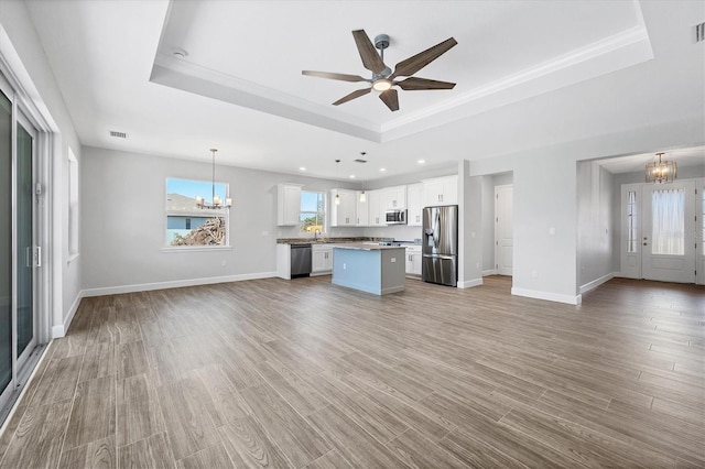 kitchen with a raised ceiling, white cabinets, and appliances with stainless steel finishes