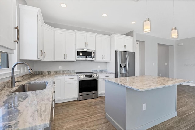 kitchen featuring white cabinets, stainless steel appliances, a kitchen island, and sink