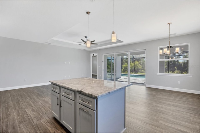 kitchen featuring light stone countertops, decorative light fixtures, ceiling fan, and dark wood-type flooring