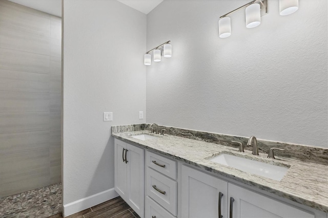 bathroom with wood-type flooring, vanity, and a tile shower