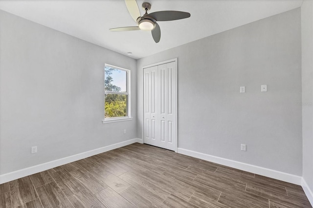 unfurnished bedroom featuring ceiling fan, a closet, and wood-type flooring