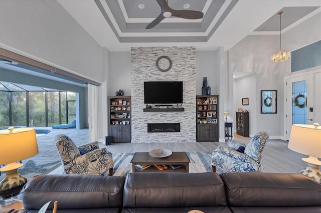 living room with a high ceiling, light wood-type flooring, and a stone fireplace