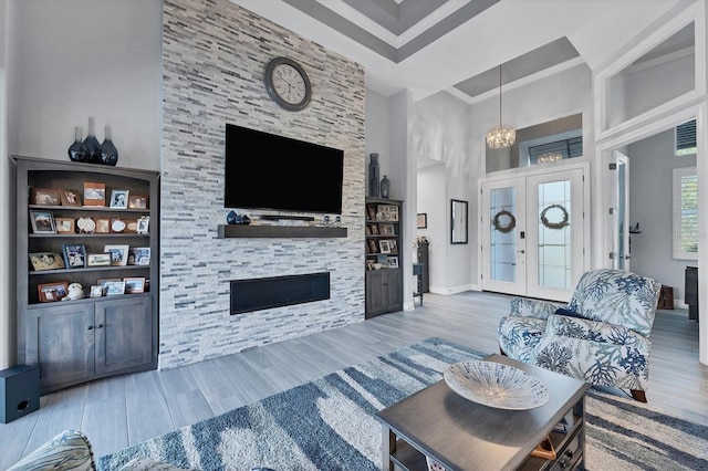 living room featuring french doors, a towering ceiling, an inviting chandelier, and hardwood / wood-style flooring