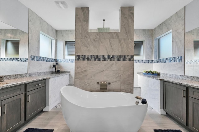 bathroom with a tub, vanity, wood-type flooring, and tile walls