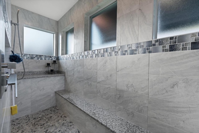 bathroom featuring a tile shower and tile walls