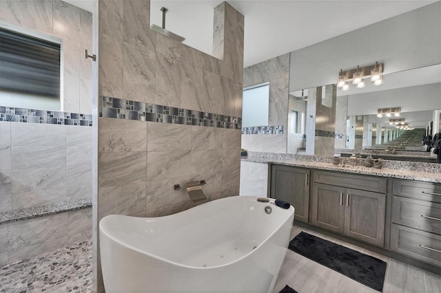 bathroom featuring plus walk in shower, vanity, and tile walls