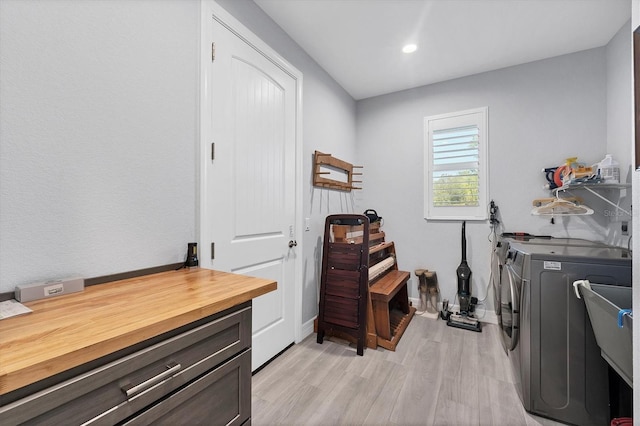 clothes washing area with washer and clothes dryer and light wood-type flooring