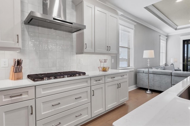 kitchen featuring light wood-type flooring, white cabinetry, stainless steel gas cooktop, and wall chimney range hood