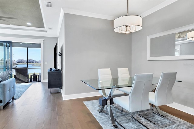 dining area featuring ceiling fan, ornamental molding, dark wood-type flooring, and a tray ceiling