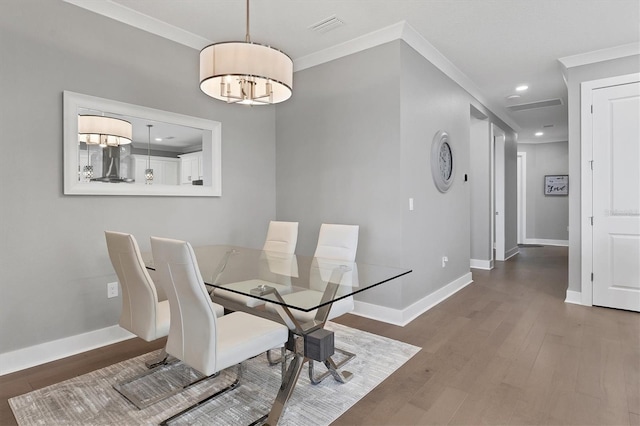 dining space with wood-type flooring, a notable chandelier, and ornamental molding