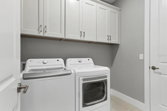 washroom featuring cabinets, light tile patterned floors, and washing machine and clothes dryer